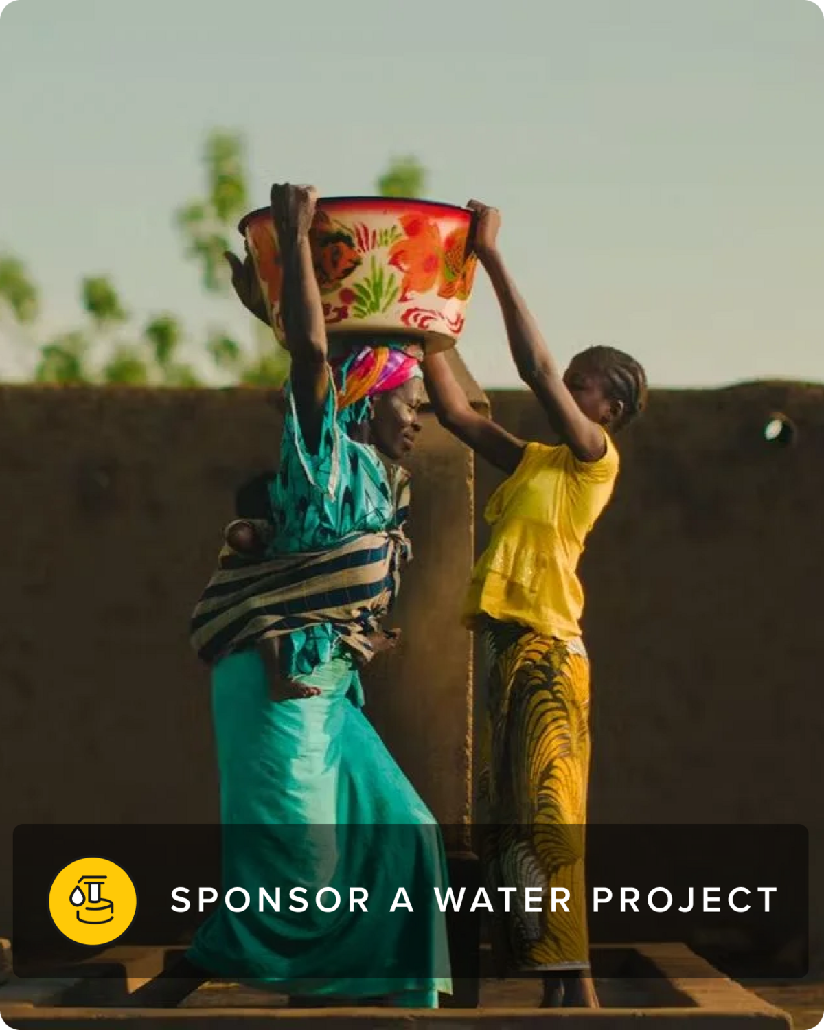 A woman and a child carry a water bucket together.