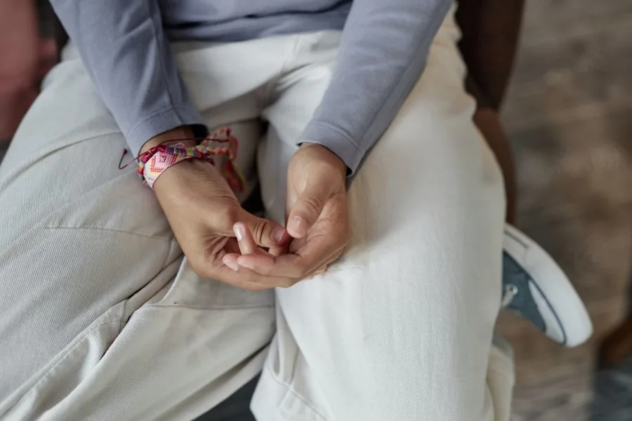 Photo of a young person's hands clasped in their lap.
