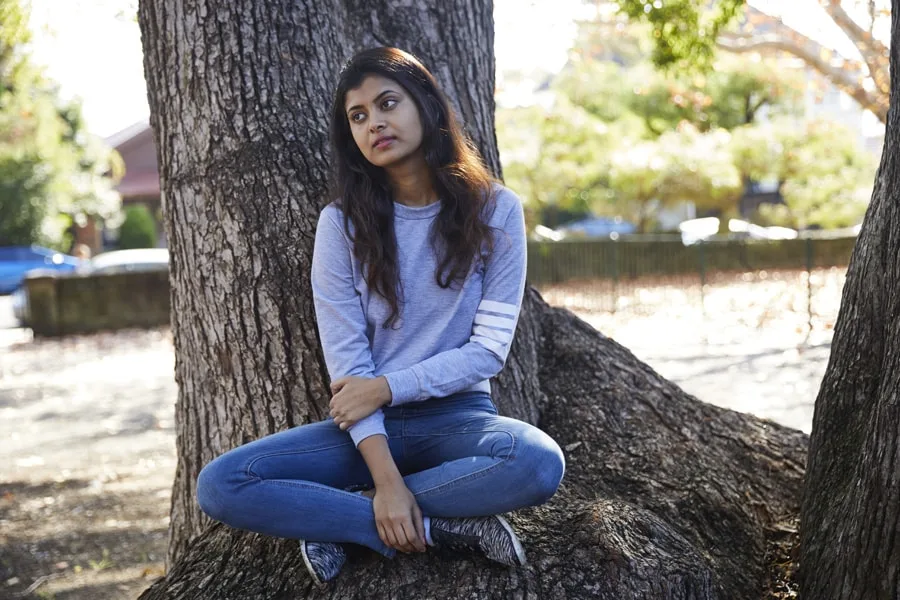 Girl sitting in park next to tree