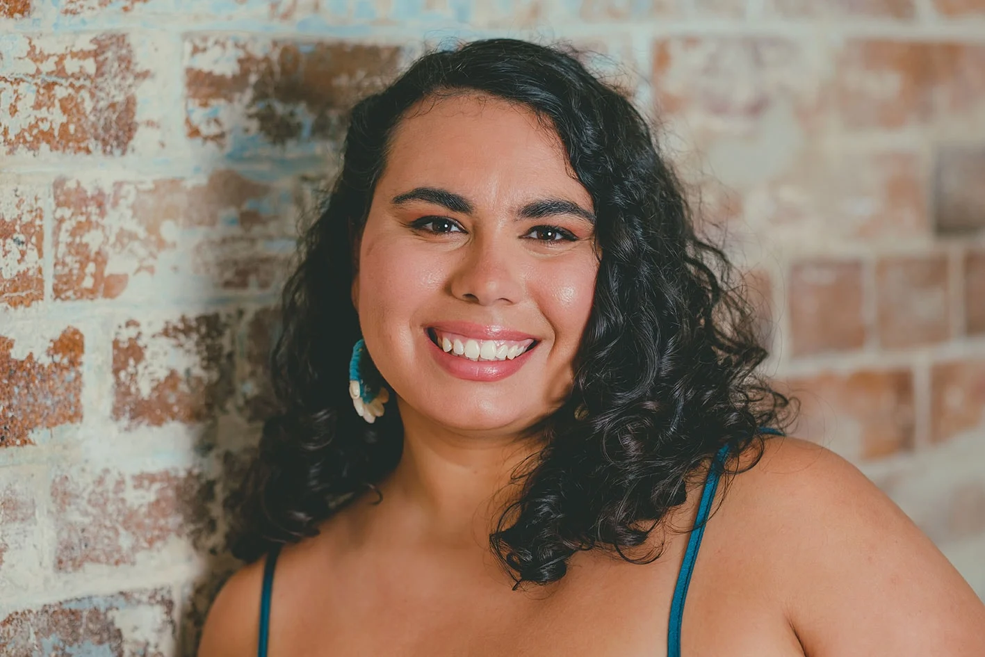 aboriginal woman smiling in front of a brick wall