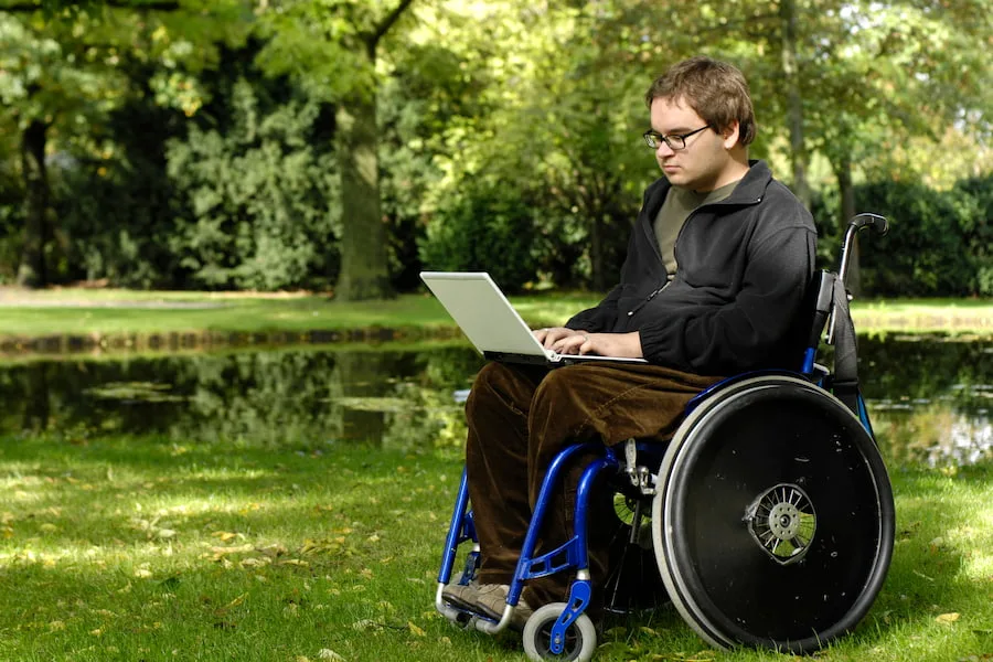 guy in wheelchair on laptop in park