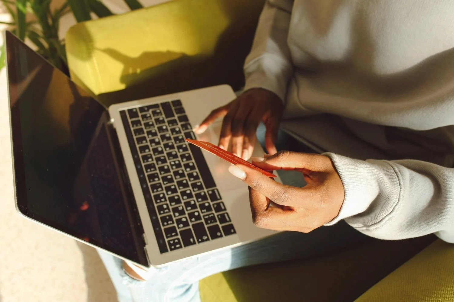 Young person makes a purchase on their laptop with their credit card in their hand.
