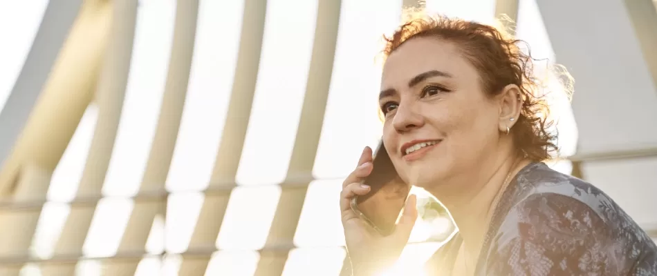 Woman sitting in sunshine on mobile phone