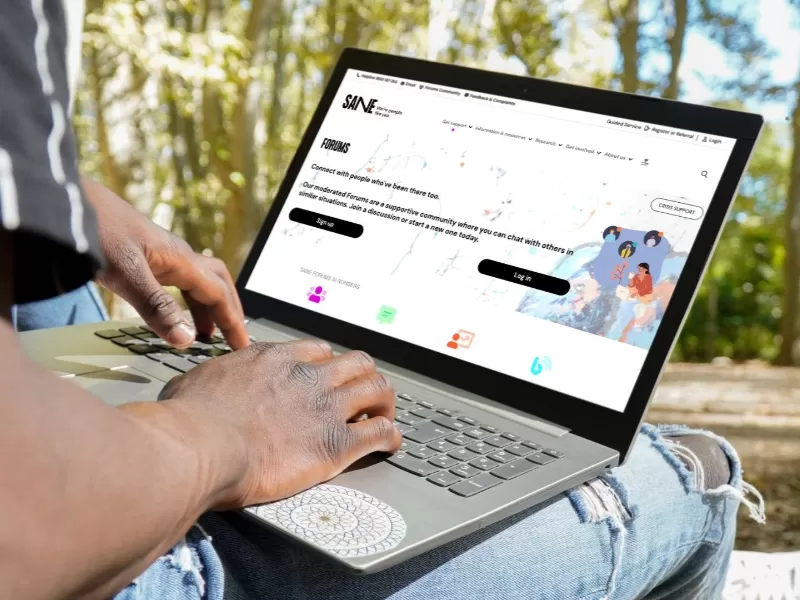 Man with laptop looking at the SANE ofurms while sitting on a park bench